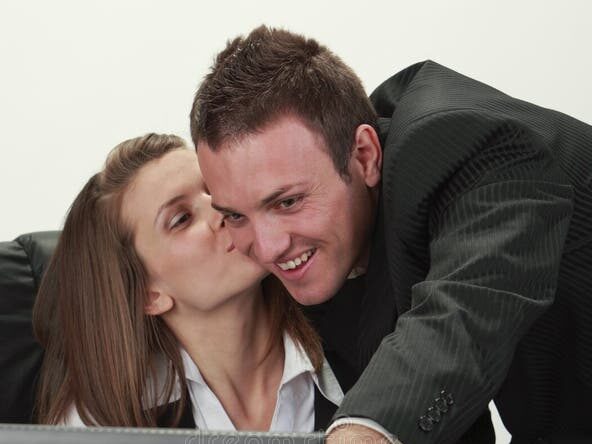 Girl at office, gives a peck on the cheek of her colleague